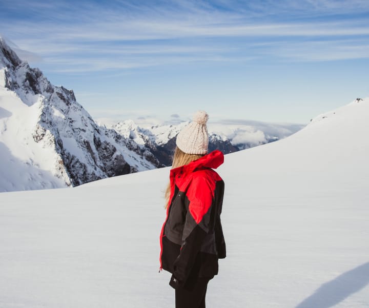 Woman standing on snow looking at mountain