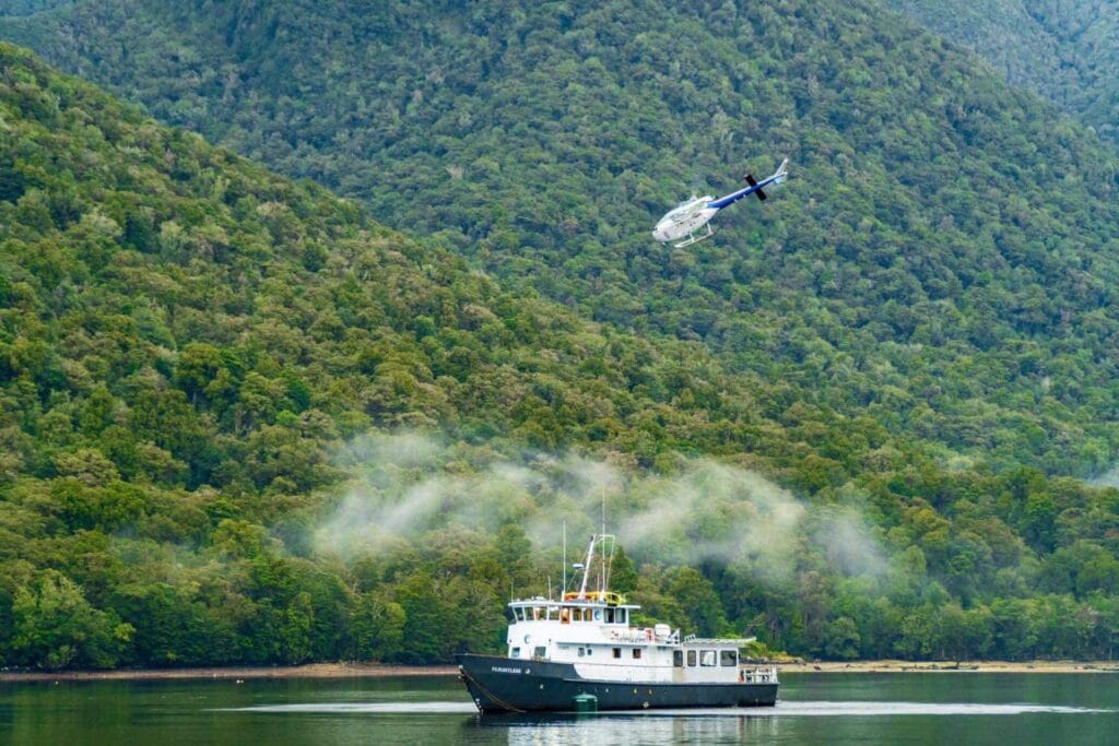 Photo of a boat on a lake with a helicopter flying above