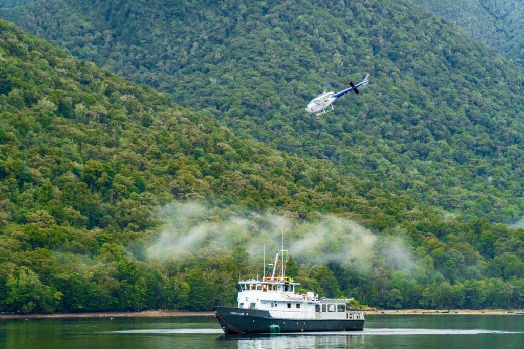 Photo of a boat on a lake with a helicopter flying above